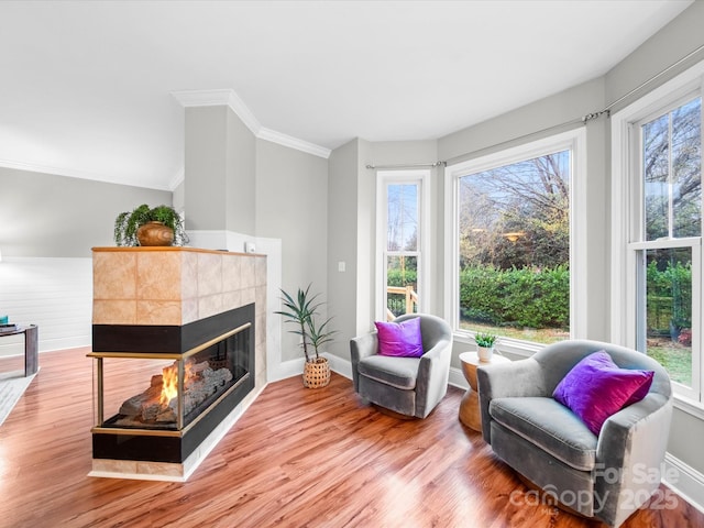 sitting room featuring hardwood / wood-style floors, crown molding, a healthy amount of sunlight, and a multi sided fireplace