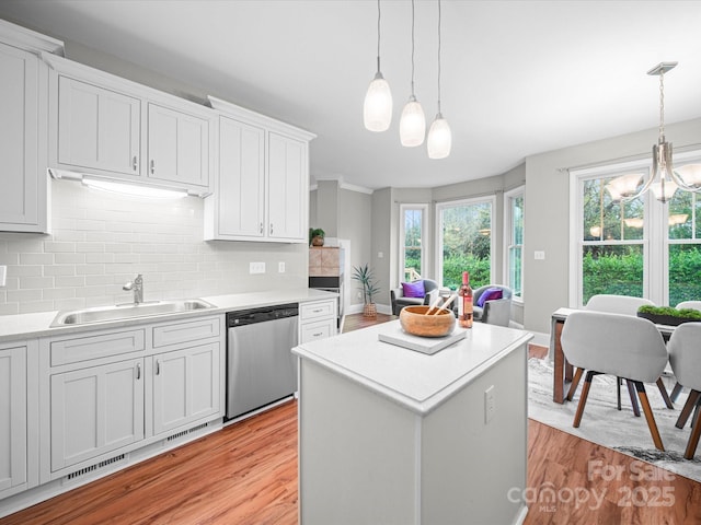 kitchen with decorative light fixtures, dishwasher, sink, and white cabinets