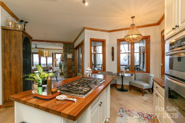 kitchen with an inviting chandelier, appliances with stainless steel finishes, butcher block countertops, and white cabinets