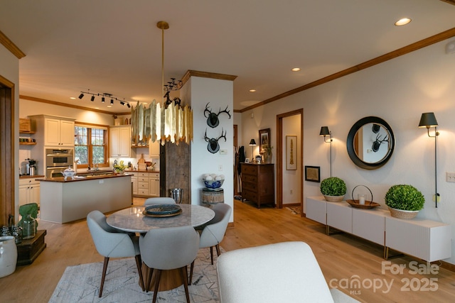 dining space with crown molding and light hardwood / wood-style floors