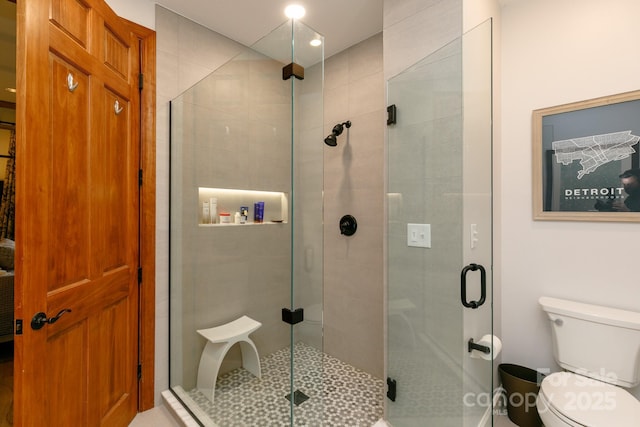 bathroom with toilet and a shower with shower door