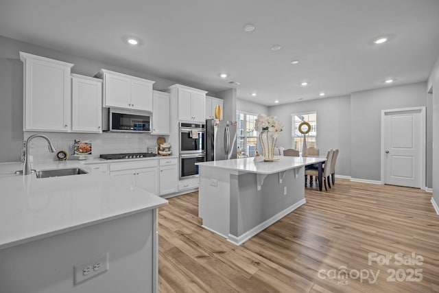 kitchen featuring a kitchen island, white cabinetry, appliances with stainless steel finishes, and sink