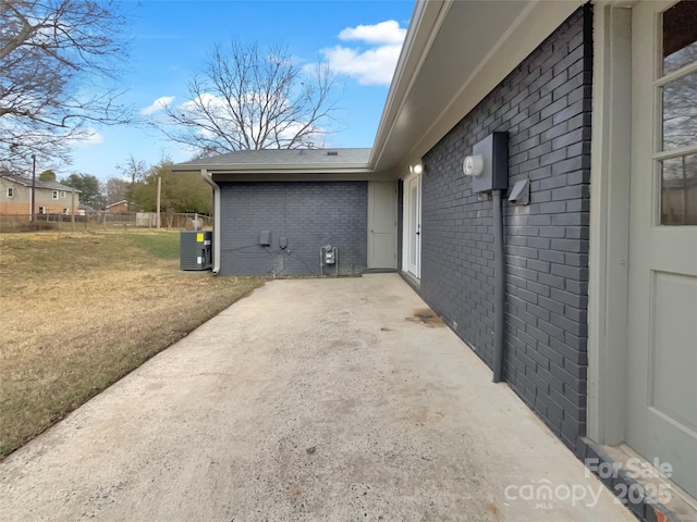 view of side of home with cooling unit, a yard, and a patio