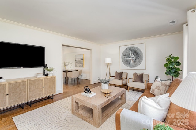 living room featuring ornamental molding, wood finished floors, visible vents, and baseboards