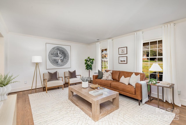 living area with light wood-style floors, baseboards, and ornamental molding