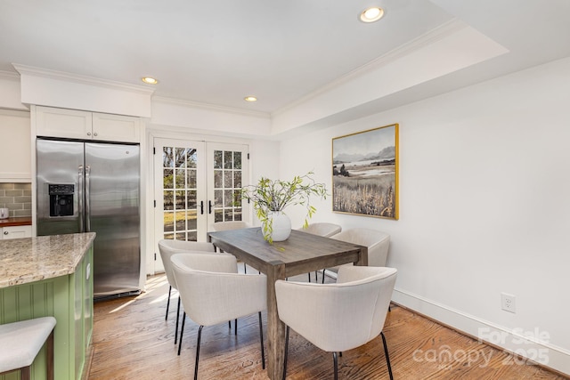 dining space with ornamental molding, french doors, and light wood finished floors