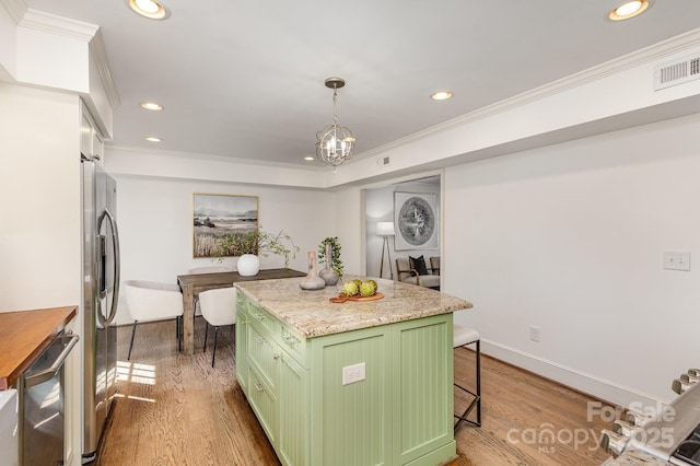 kitchen featuring stainless steel appliances, visible vents, green cabinets, a kitchen island, and a kitchen breakfast bar