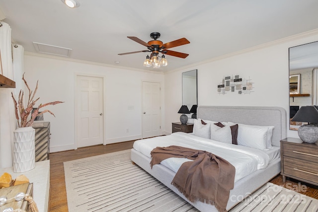 bedroom featuring baseboards, light wood finished floors, attic access, and crown molding