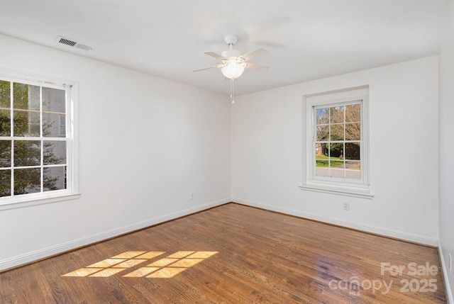 empty room featuring ceiling fan, wood finished floors, visible vents, and baseboards