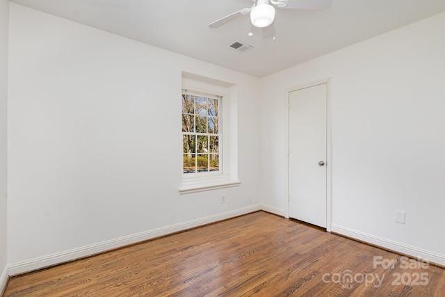 empty room featuring visible vents, ceiling fan, baseboards, and wood finished floors