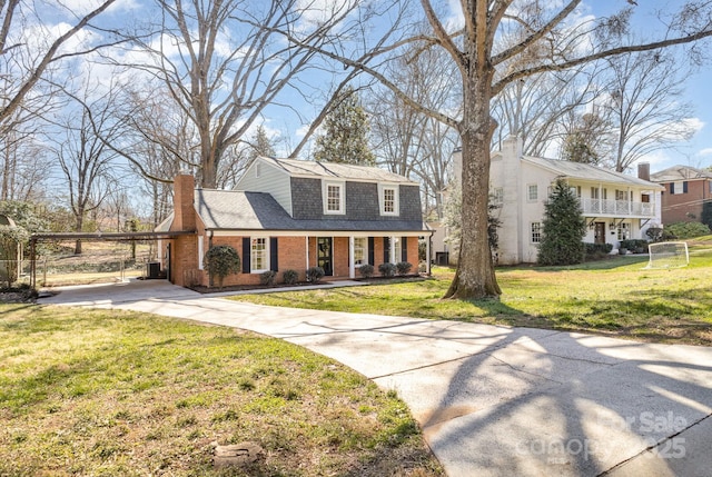 view of front facade featuring a front yard, driveway, a chimney, and brick siding