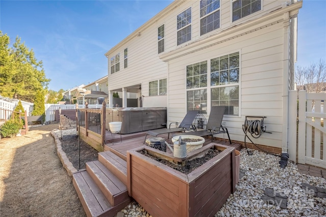 rear view of property with cooling unit, a wooden deck, a hot tub, and an outdoor fire pit