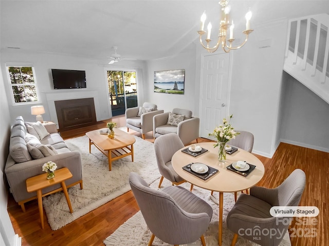 dining space with ceiling fan with notable chandelier, wood-type flooring, and a healthy amount of sunlight