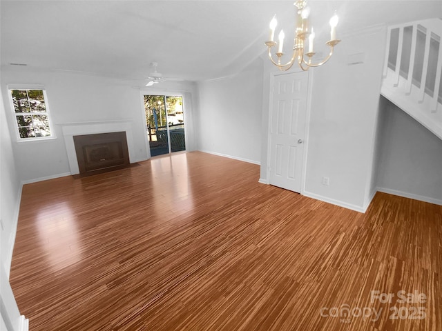 unfurnished living room with wood-type flooring, ceiling fan with notable chandelier, and a wealth of natural light