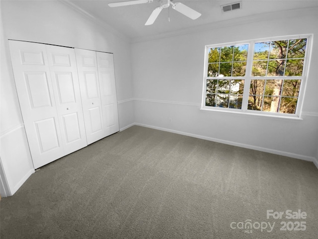 unfurnished bedroom featuring crown molding, ceiling fan, carpet, vaulted ceiling, and a closet