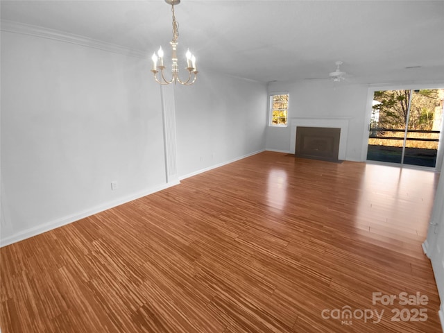 unfurnished living room with hardwood / wood-style flooring, ornamental molding, and ceiling fan with notable chandelier