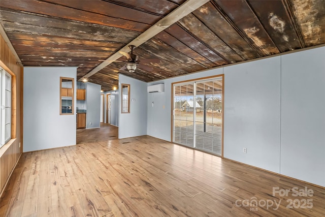 unfurnished living room featuring ceiling fan, lofted ceiling, a wall unit AC, and light hardwood / wood-style floors