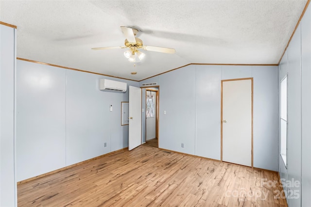 unfurnished bedroom featuring lofted ceiling, a wall unit AC, crown molding, a textured ceiling, and light hardwood / wood-style flooring