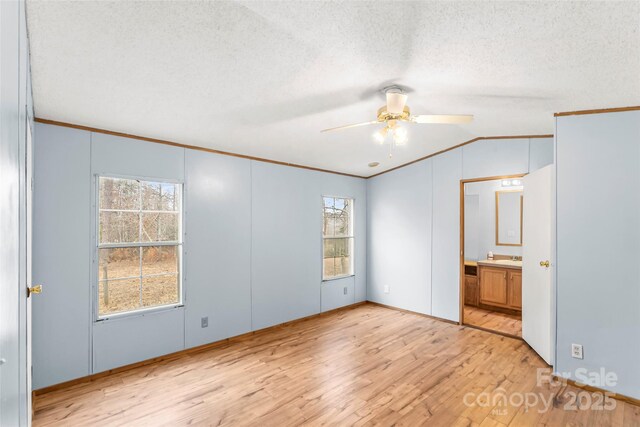 unfurnished bedroom with crown molding, vaulted ceiling, a textured ceiling, and light hardwood / wood-style floors