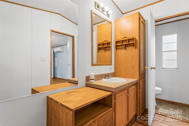 bathroom with ornamental molding, vanity, toilet, and a wall unit AC