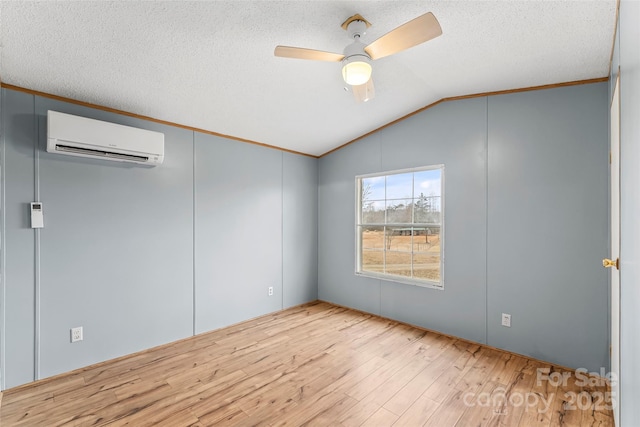 unfurnished room featuring lofted ceiling, a textured ceiling, light hardwood / wood-style flooring, a wall unit AC, and ceiling fan