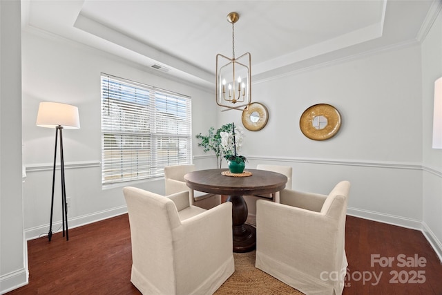 dining room with dark hardwood / wood-style flooring, ornamental molding, a raised ceiling, and a chandelier