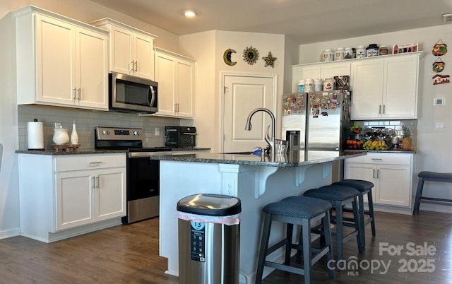 kitchen with stainless steel appliances, sink, a center island with sink, and white cabinets