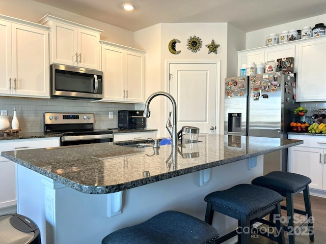 kitchen featuring a kitchen island with sink, sink, white cabinets, and appliances with stainless steel finishes