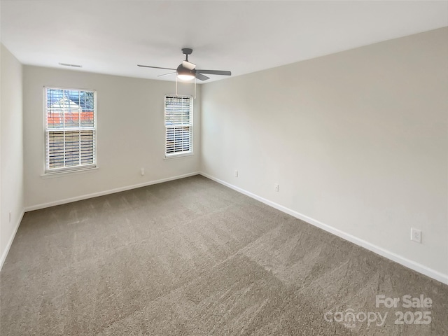 carpeted spare room featuring ceiling fan and a wealth of natural light