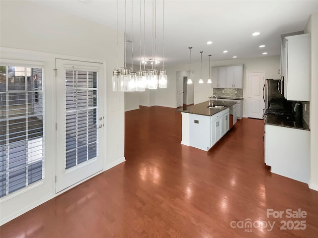 kitchen featuring a kitchen island with sink, dark hardwood / wood-style floors, tasteful backsplash, white cabinets, and decorative light fixtures