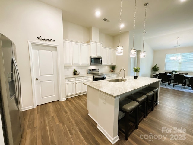 kitchen with sink, white cabinetry, a kitchen island with sink, hanging light fixtures, and stainless steel appliances