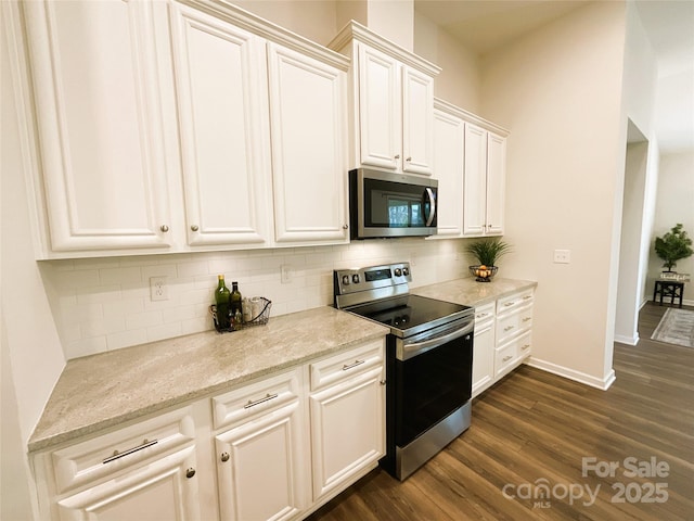 kitchen featuring light stone counters, dark wood-type flooring, tasteful backsplash, and appliances with stainless steel finishes