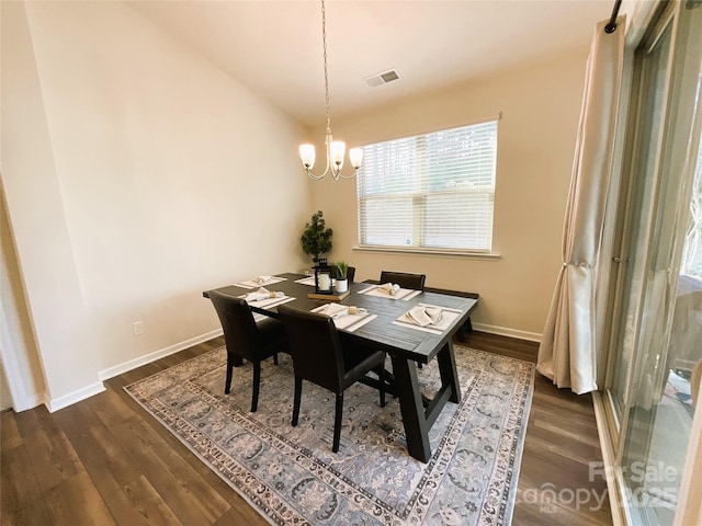 dining space with dark hardwood / wood-style floors and a chandelier