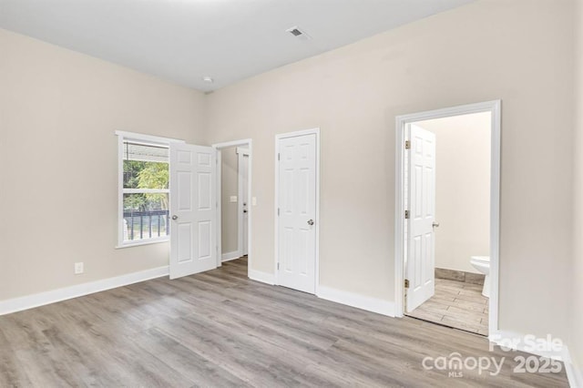 unfurnished bedroom with light wood-type flooring and ensuite bath