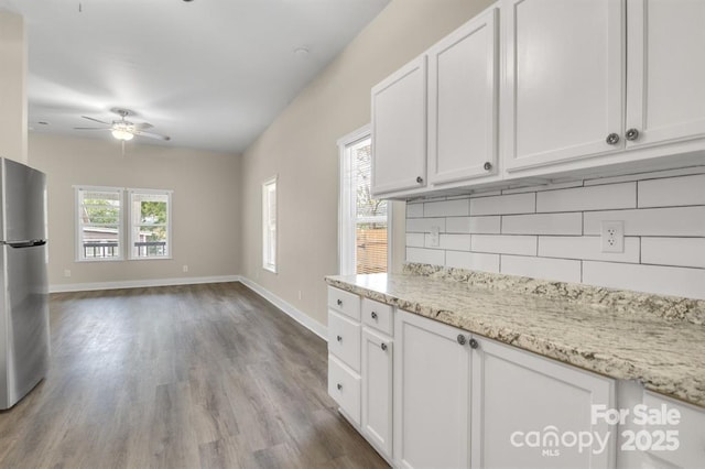 kitchen with plenty of natural light, stainless steel fridge, decorative backsplash, and white cabinets