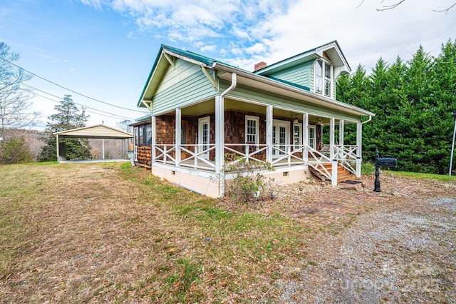 view of front of house featuring a carport, covered porch, and a front lawn