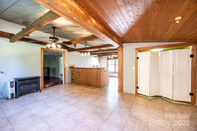 unfurnished living room featuring vaulted ceiling with beams, wooden ceiling, light tile patterned floors, a wood stove, and ceiling fan