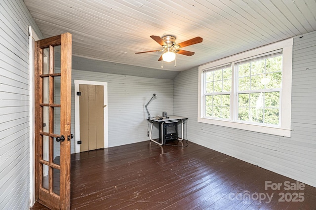 spare room featuring wood walls, lofted ceiling, ceiling fan, dark wood-type flooring, and wooden ceiling