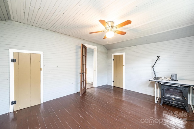 interior space with vaulted ceiling, wooden ceiling, a wood stove, dark hardwood / wood-style floors, and ceiling fan