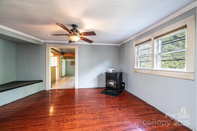 spare room featuring hardwood / wood-style flooring, ceiling fan, ornamental molding, and a wood stove