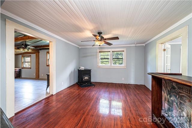 unfurnished room featuring crown molding, ceiling fan, dark hardwood / wood-style flooring, and a wood stove