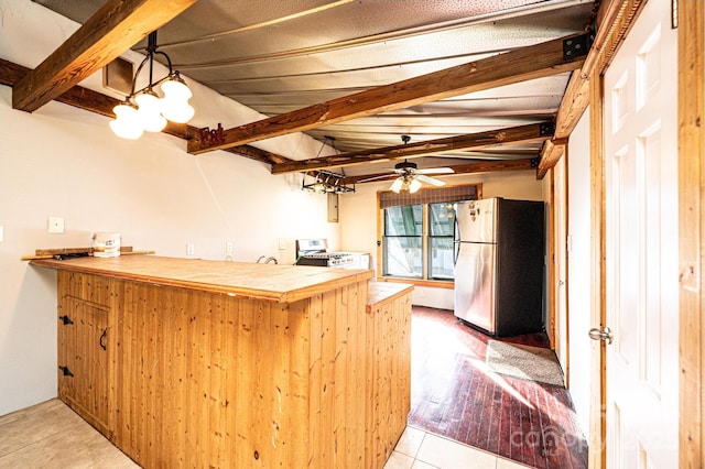 kitchen featuring light tile patterned floors, tile counters, kitchen peninsula, stainless steel appliances, and beam ceiling