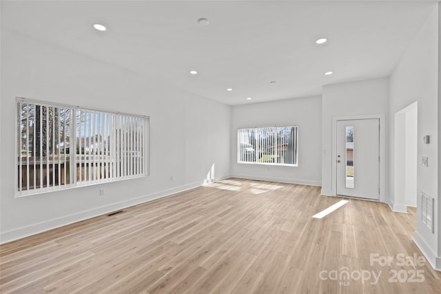 unfurnished living room with baseboards, light wood-type flooring, visible vents, and recessed lighting