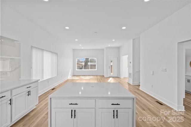 kitchen with light wood-style floors, white cabinets, light countertops, and visible vents