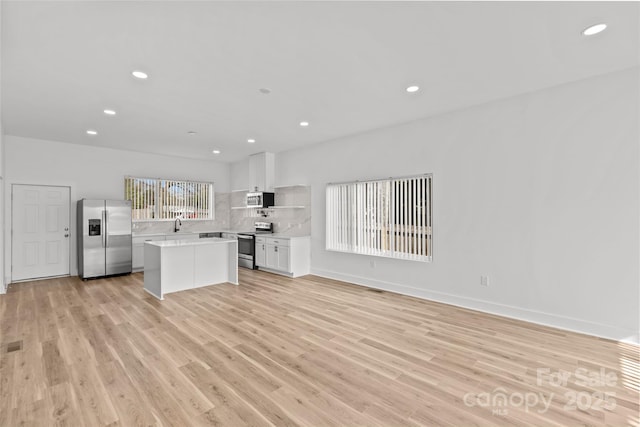 kitchen with open shelves, stainless steel appliances, light countertops, white cabinets, and a kitchen island