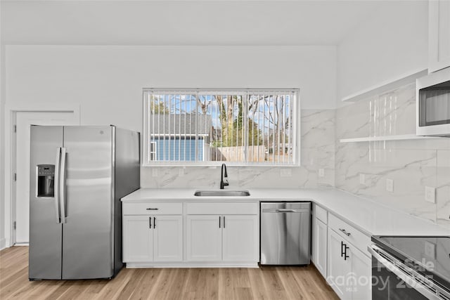 kitchen with white cabinetry, stainless steel appliances, a sink, and light countertops