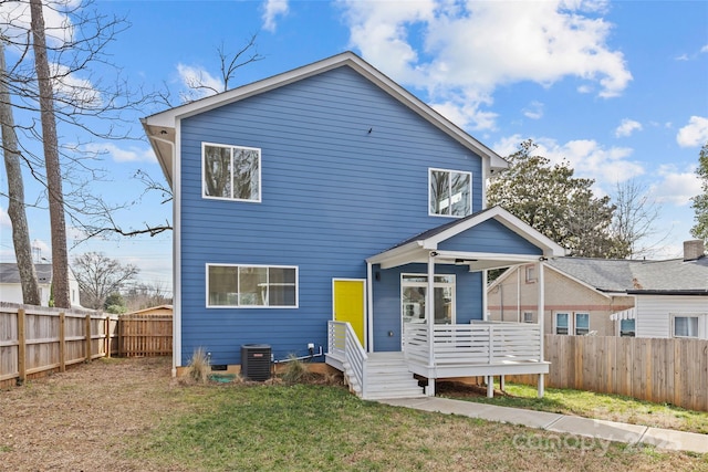 view of front of property featuring a front yard, a fenced backyard, and central AC unit