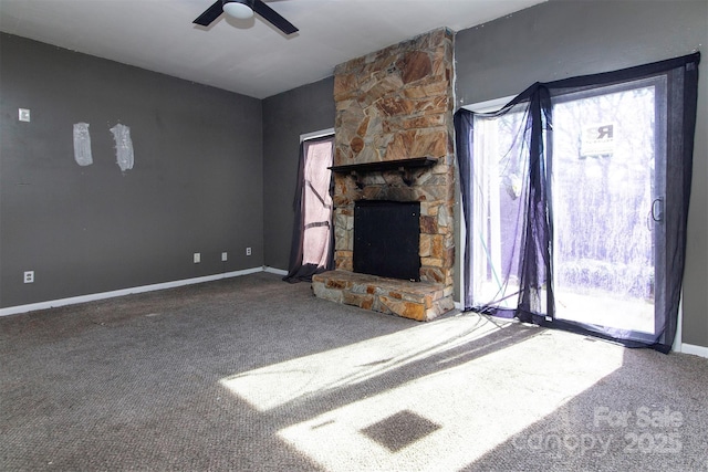 unfurnished living room with ceiling fan, a stone fireplace, and carpet floors