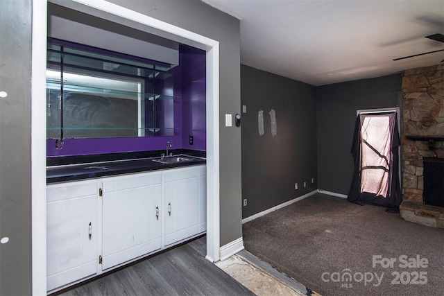 bathroom featuring hardwood / wood-style flooring, vanity, a stone fireplace, and ceiling fan