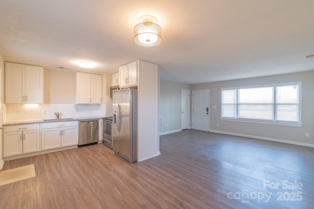 kitchen featuring white cabinetry, backsplash, dark wood-type flooring, and stainless steel appliances